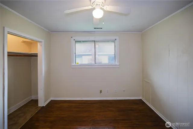 an empty room with wooden floor chandelier fan and windows