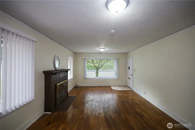 an empty room with wooden floor cabinet and windows