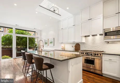a kitchen with stainless steel appliances granite countertop a table chairs stove and cabinets