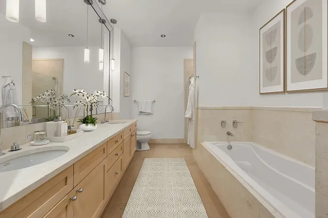 a bedroom with a bed and a lamp on dresser with wooden floor