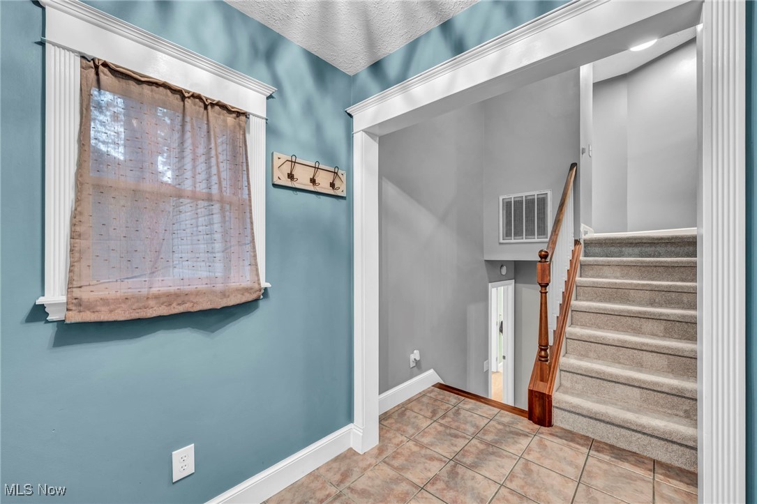 47655 Cooper Foster Park Road Amherst, OH 44001 - Photo 3 of 49 Tiled foyer entrance with stairs and a textured ceiling