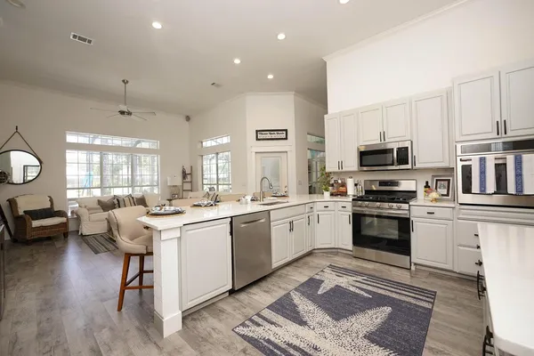 a kitchen with a sink stove cabinets and wooden floor