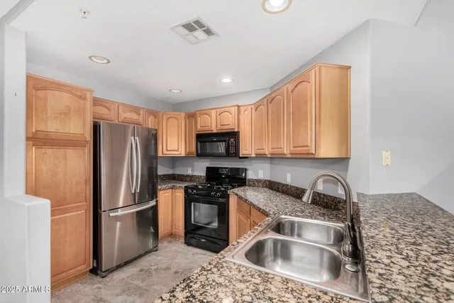 a kitchen with stainless steel appliances granite countertop a refrigerator sink and stove