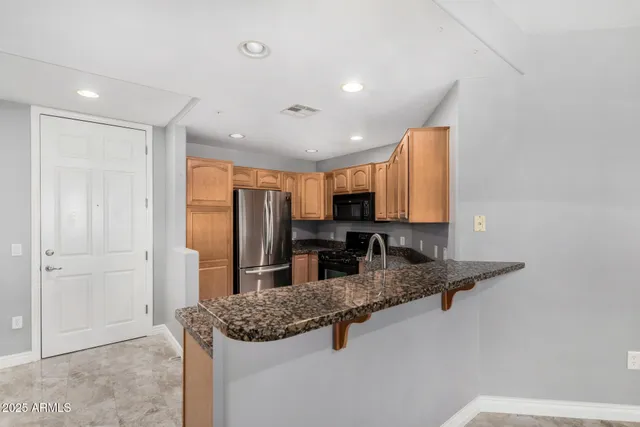 a kitchen with stainless steel appliances granite countertop a sink refrigerator and cabinets