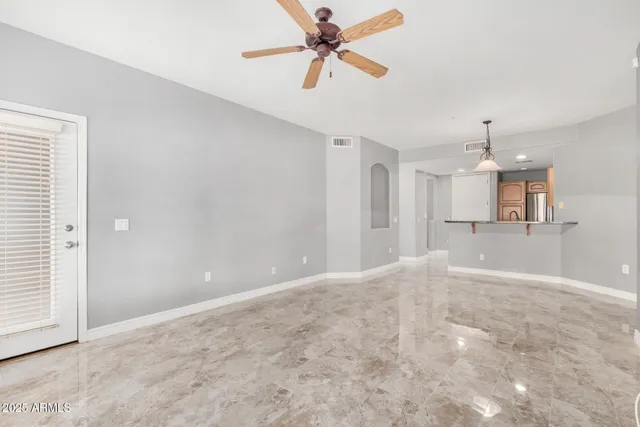 an empty room with chandelier fan and windows