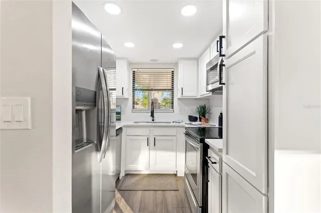 a kitchen with kitchen island a counter top space a refrigerator and cabinets