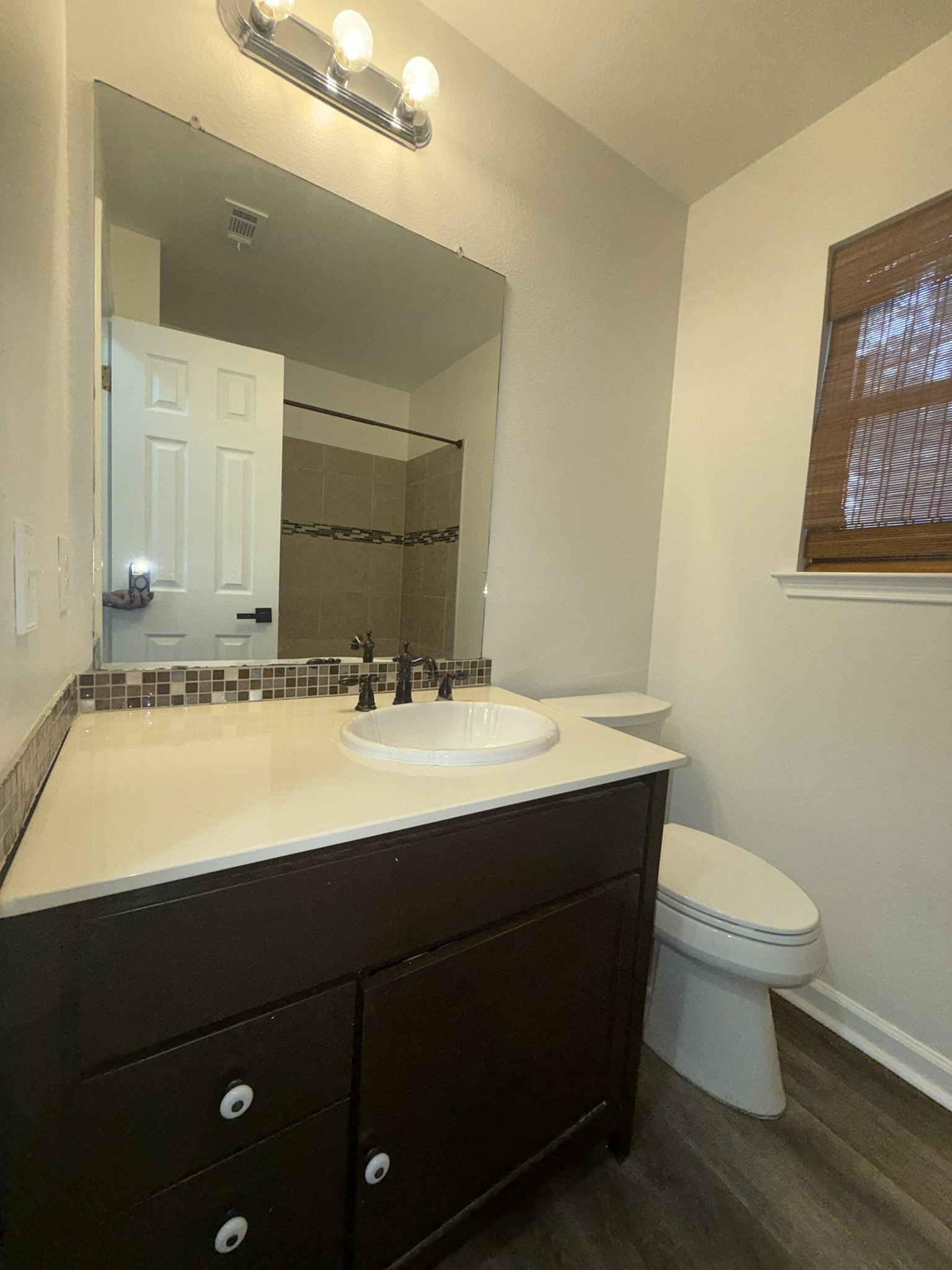 5807 Teri Road Austin, TX 78744 - Photo 10 of 20 Bathroom featuring a dark wood-finish vanity with a light-toned countertop, a rectangular mirror, a three-light vanity fixture, and wood-finish flooring