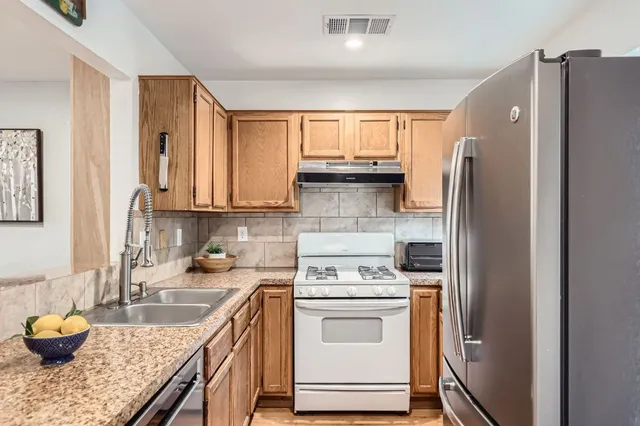a kitchen with stainless steel appliances granite countertop a refrigerator sink and stove