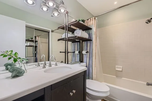 a bathroom with a sink a toilet a large mirror and shower