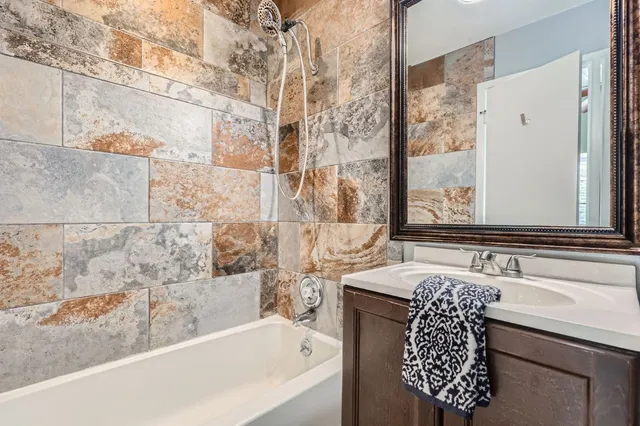 a bathroom with a granite countertop sink and a bathtub