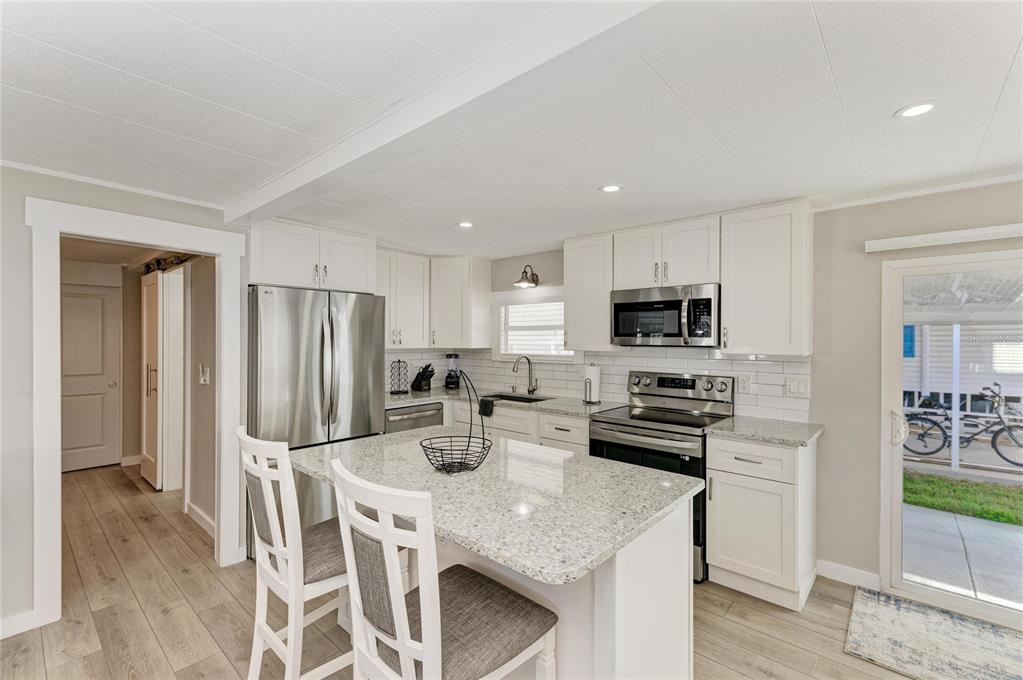 10315 Cortez Road West, Unit 61 Bradenton, FL 34210 - Photo 14 of 46 a kitchen with stainless steel appliances granite countertop a stove a refrigerator a sink a dining table and chairs