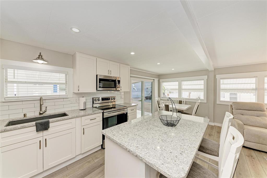 10315 Cortez Road West, Unit 61 Bradenton, FL 34210 - Photo 16 of 46 a kitchen with stainless steel appliances granite countertop a sink dishwasher a stove and white cabinets with wooden floor