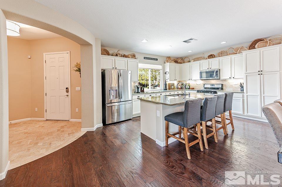 2220 Trakehner Lane Reno, NV 89521 - Photo 4 of 25 a kitchen with stainless steel appliances granite countertop a refrigerator a stove top oven and a dining table with wooden floor