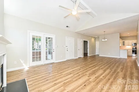 a view of an empty room with wooden floor and a ceiling fan