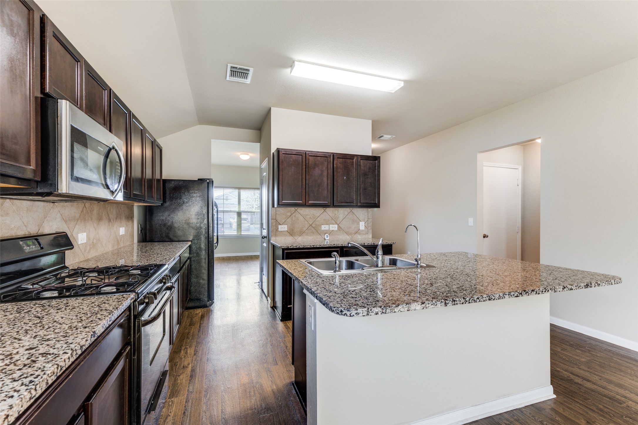 801 Silver Wing Drive Austin, TX 78725 - Photo 10 of 29 a kitchen with stainless steel appliances granite countertop a stove top oven a sink dishwasher and cabinets with wooden floor