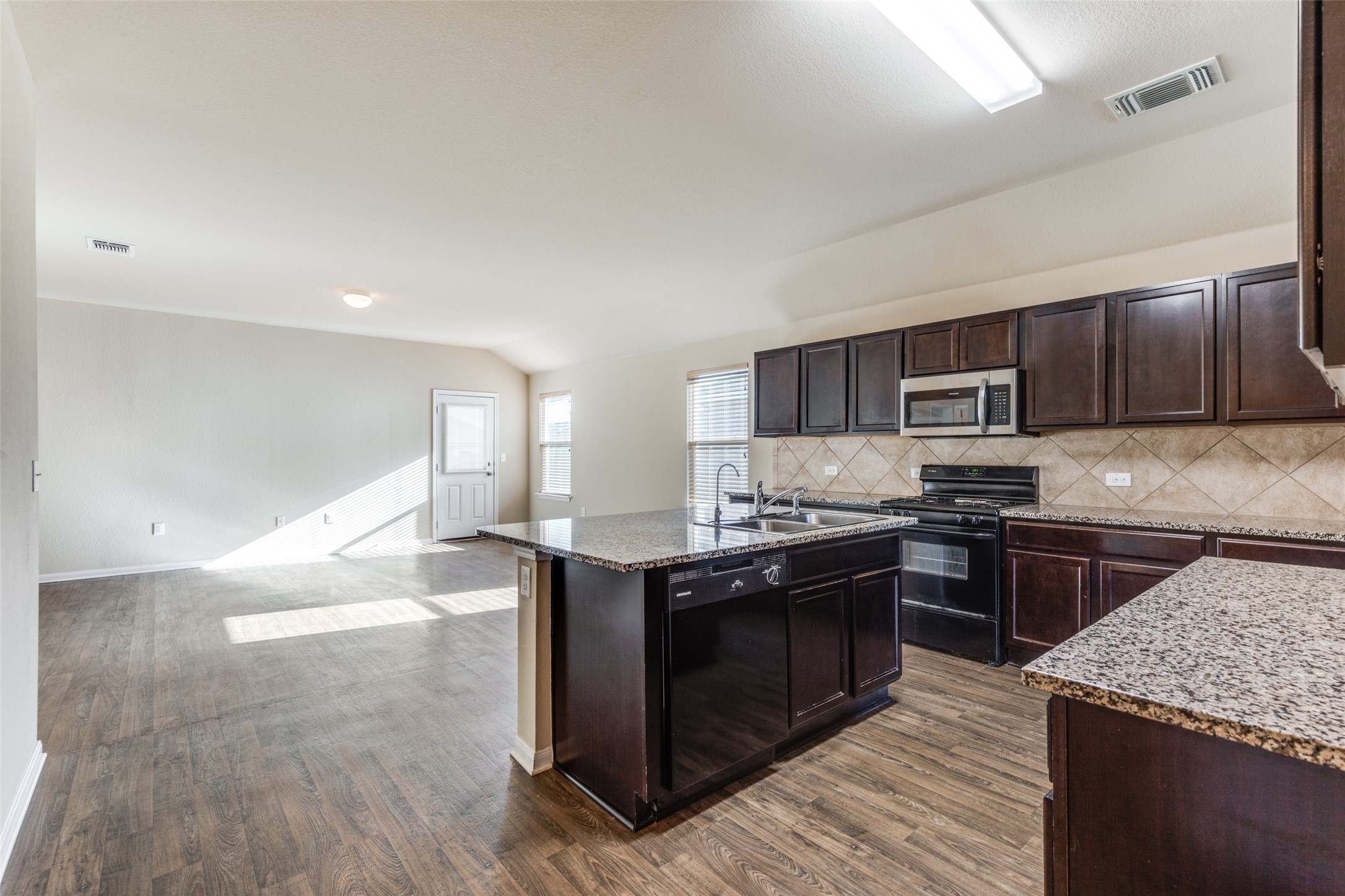 801 Silver Wing Drive Austin, TX 78725 - Photo 11 of 29 a kitchen with stainless steel appliances granite countertop a stove top oven a sink dishwasher a dining table and chairs with wooden floors