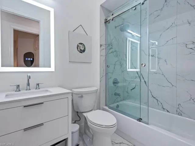 a bathroom with a granite countertop toilet a sink and a mirror