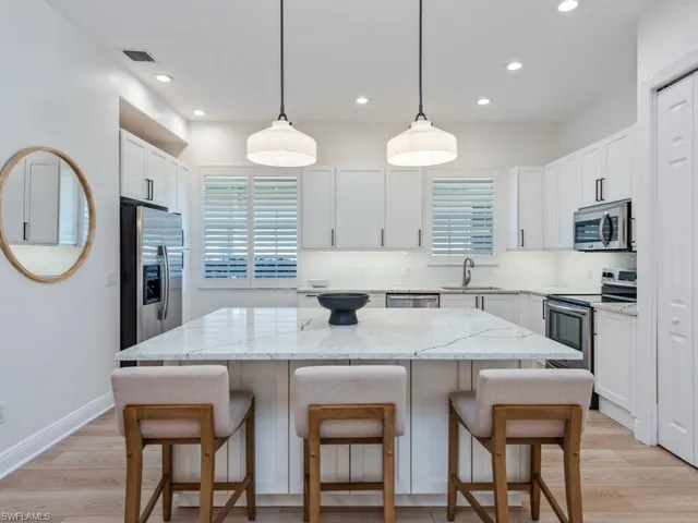 a kitchen with cabinets a center island stainless steel appliances and a chandelier