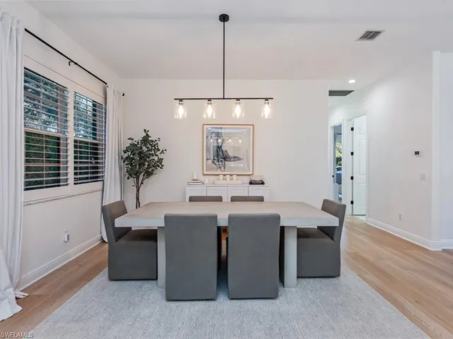 a room with granite countertop a sink dishwasher a dining table and chairs with wooden floor