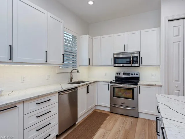 a kitchen with granite countertop a sink stainless steel appliances and white cabinets
