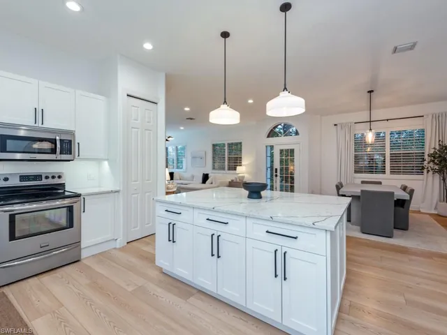 a kitchen with kitchen island white cabinets and stainless steel appliances