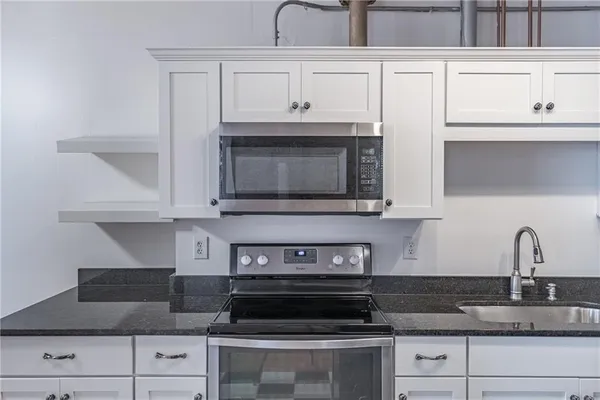 a kitchen with granite countertop white cabinets and a stove