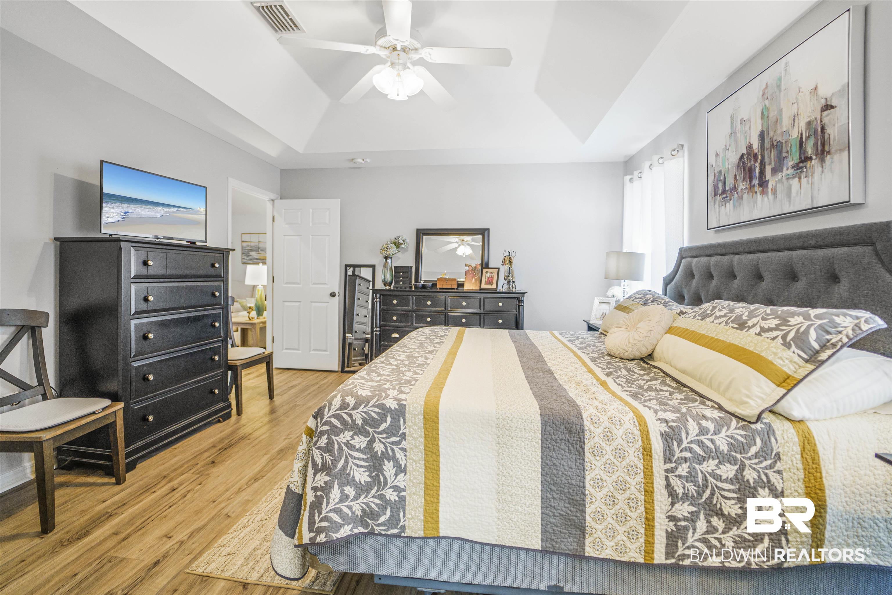 4620 Pine Boulevard Orange Beach, AL 36561 - Photo 15 of 49 Bedroom featuring a tray ceiling, wood finished floors, and ceiling fan