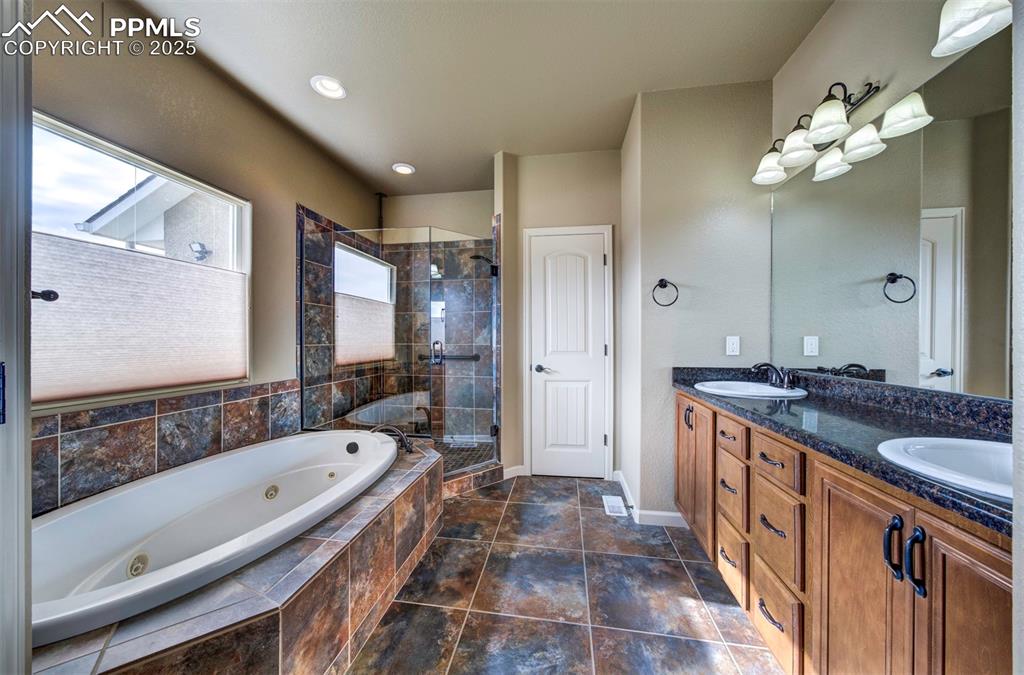 24484 Gale Road Pueblo, CO 81006 - Photo 25 of 43 a spacious bathroom with a granite countertop tub a double vanity sink a vanity and a large mirror