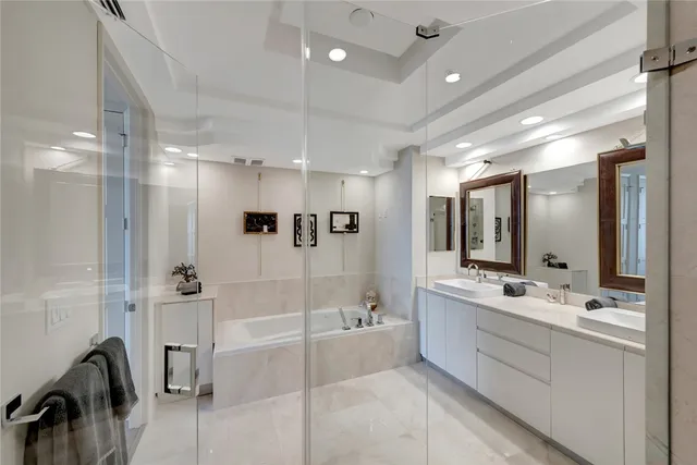 a bathroom with a double vanity sink a mirror a bathtub and shower