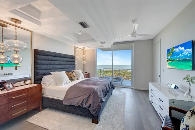 a spacious bedroom with a bed and a flat tv screen on dresser