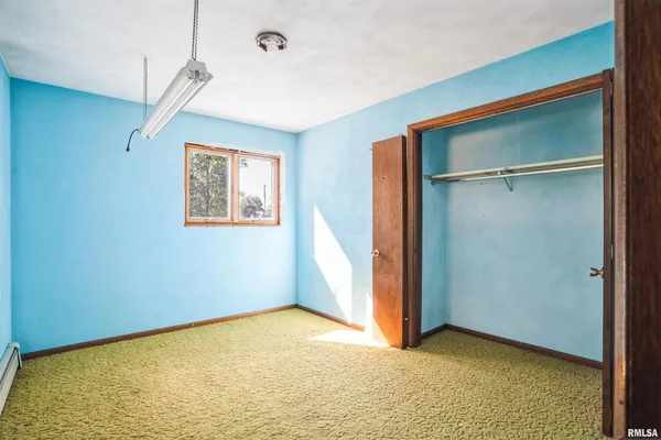 a view of an empty room with closet and a window