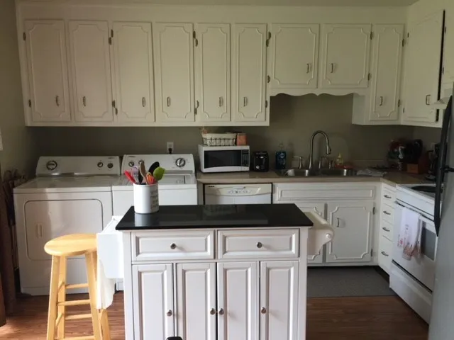 a kitchen with granite countertop white cabinets and white appliances
