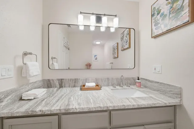 a bathroom with a granite countertop sink and a mirror