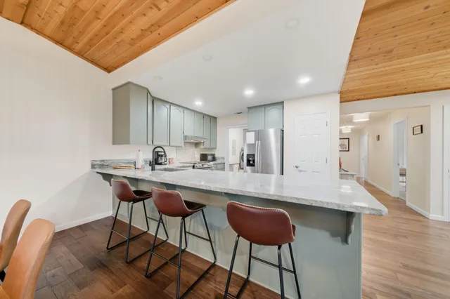 a kitchen with stainless steel appliances granite countertop a table chairs sink and cabinets