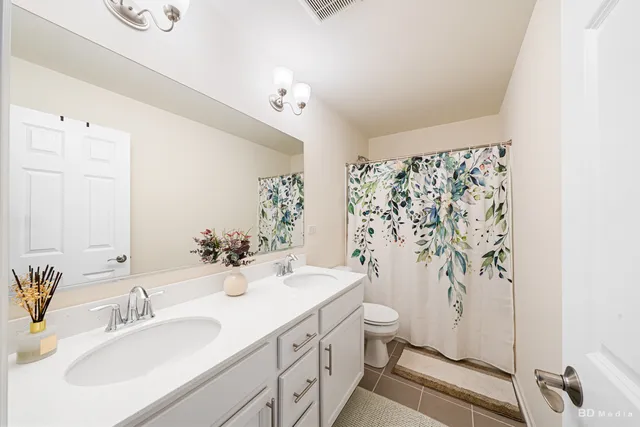a bathroom with a double vanity sink toilet and shower