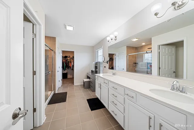 a large bathroom with a double vanity sink a toilet a mirror and shower