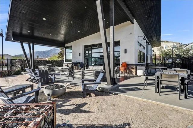 a view of a patio with dining table and chairs under an umbrella with a ceiling fan