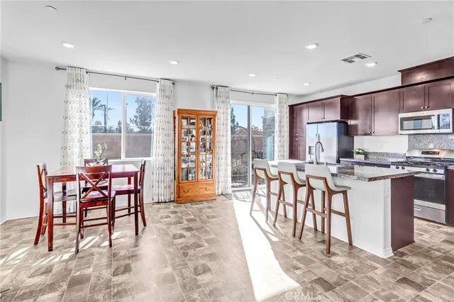 a dining area with stainless steel appliances a dining table chairs and view kitchen