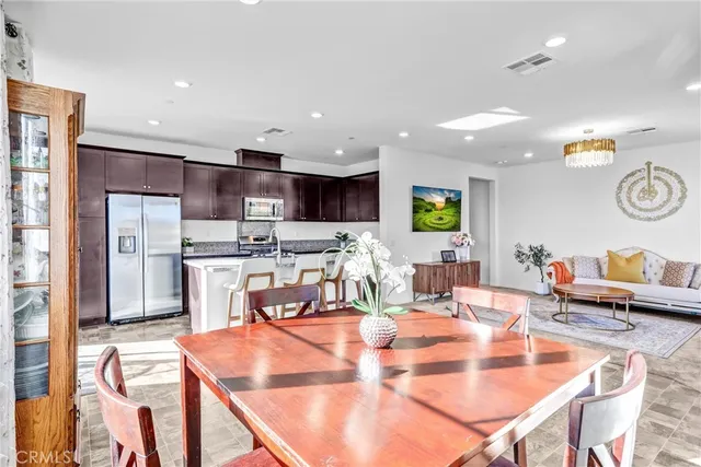 a kitchen with stainless steel appliances kitchen island granite countertop a table chairs and a refrigerator
