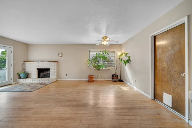 a view of an empty room with wooden floor and a fireplace