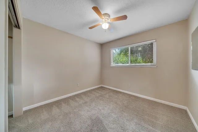 an empty room with windows and ceiling fan