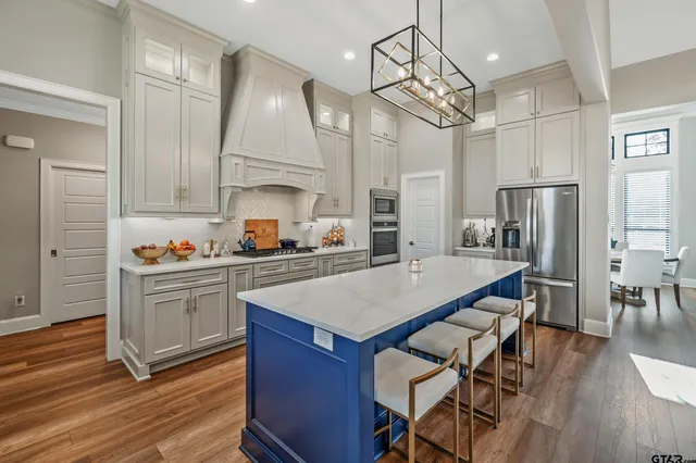 a kitchen with a refrigerator a sink dishwasher a stove and white cabinets with wooden floor