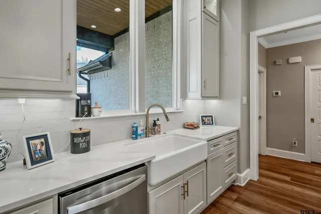 a kitchen with stainless steel appliances a sink dishwasher and cabinets with wooden floor