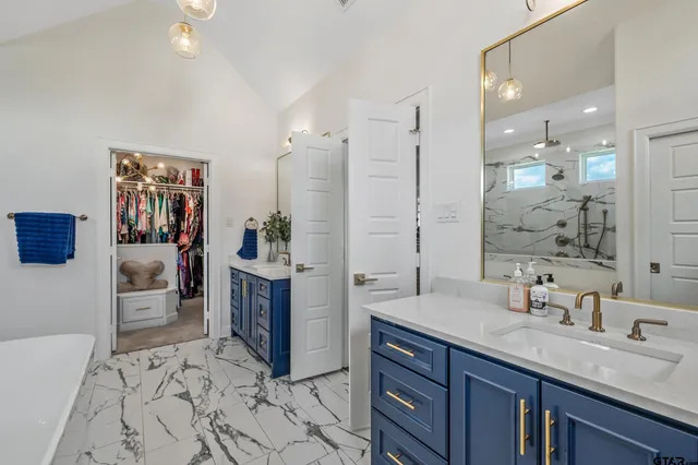 a spacious bathroom with a sink double vanity granite tub shower and a mirror