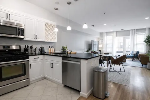 a kitchen with stainless steel appliances granite countertop a stove a sink a refrigerator a microwave a dining table and chairs