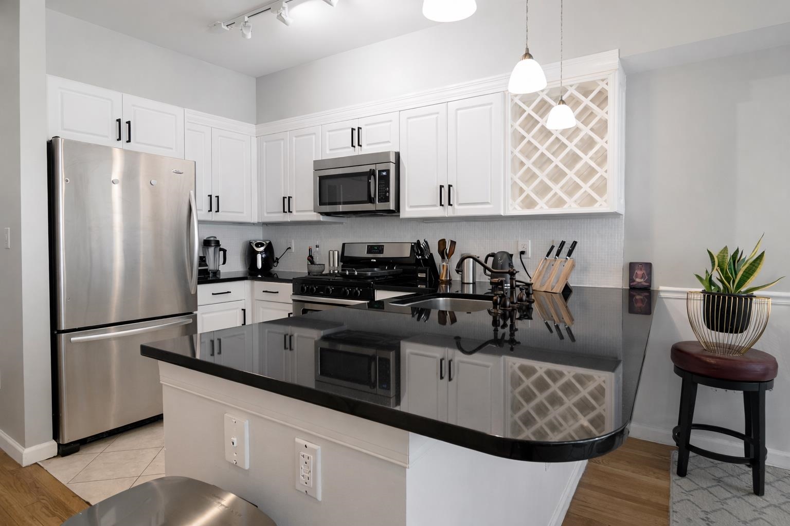 901 Madison Street, Unit 5F Hoboken, NJ 07030 - Photo 9 of 20 a kitchen with stainless steel appliances granite countertop a refrigerator a sink a stove a dining table and chairs with wooden floor