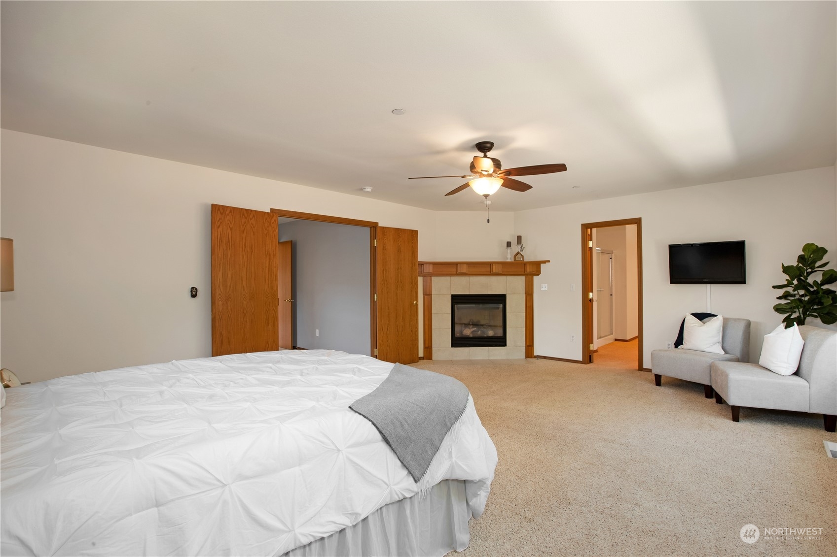 3139 Walker Road DuPont, WA 98327 - Photo 23 of 40 a spacious bedroom with a large bed a fireplace and a chandelier