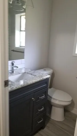a bathroom with a granite countertop toilet sink and mirror