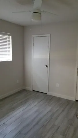 an empty room with wooden floor & windows