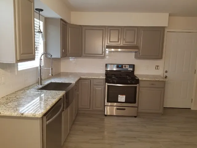 a kitchen with granite countertop a stove sink and cabinets